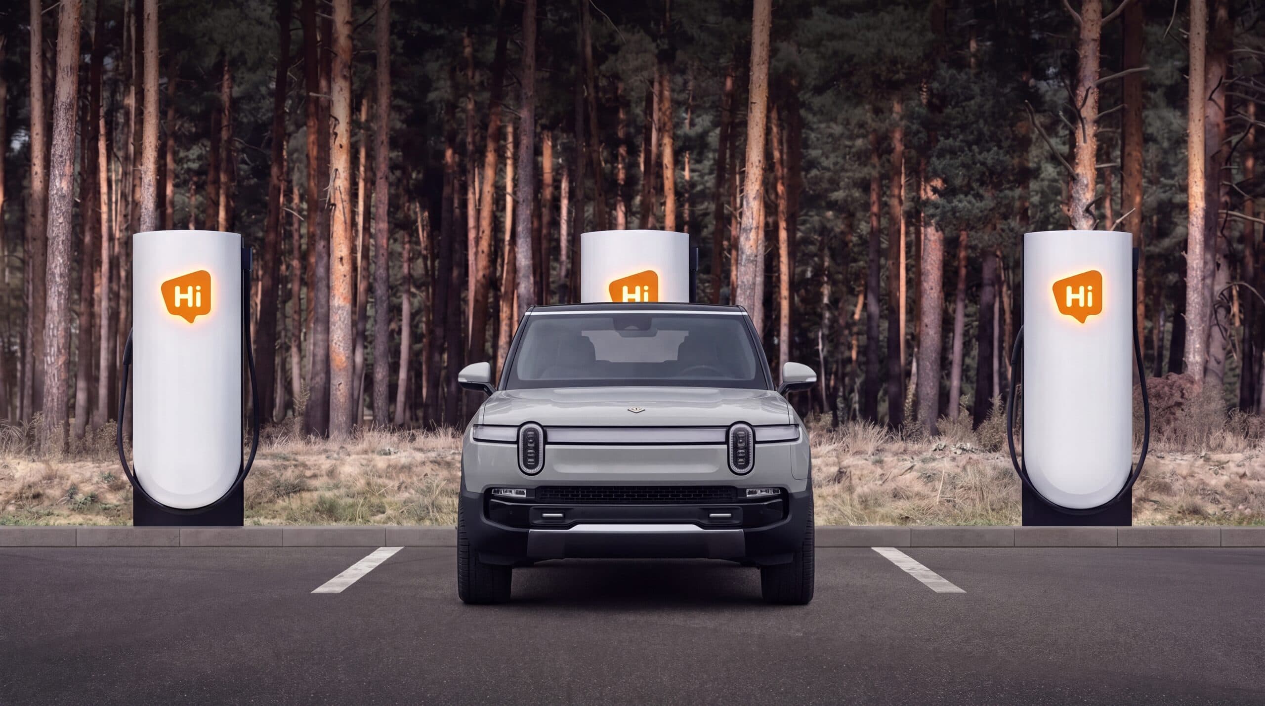 A light grey Rivian R1S parked between HiON pillars on a forest pull-off, each matte-white face marked with the glowing orange Hi badge.